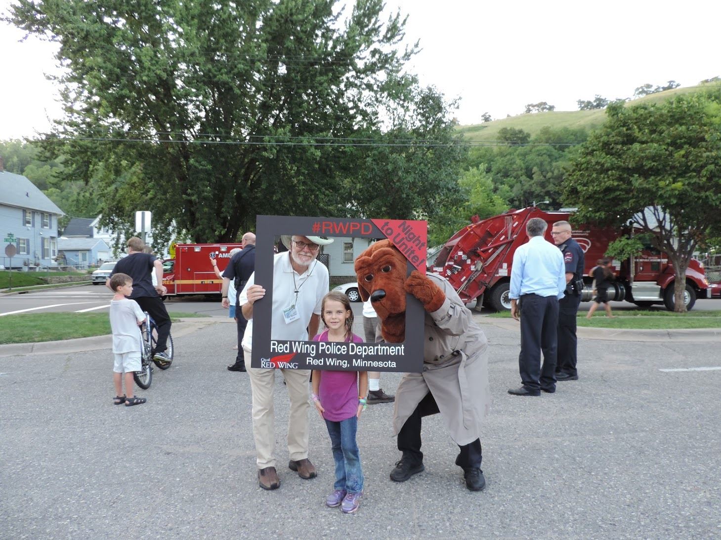 Girl, man, and police mascot pose at night to unite