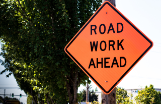 Road work ahead sign with trees in background