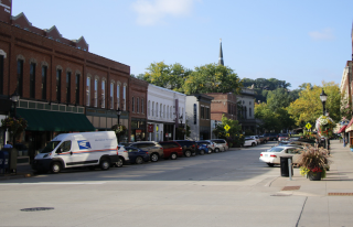 Vehicles diagonally parked in front of storefronts on both sides of Third Street
